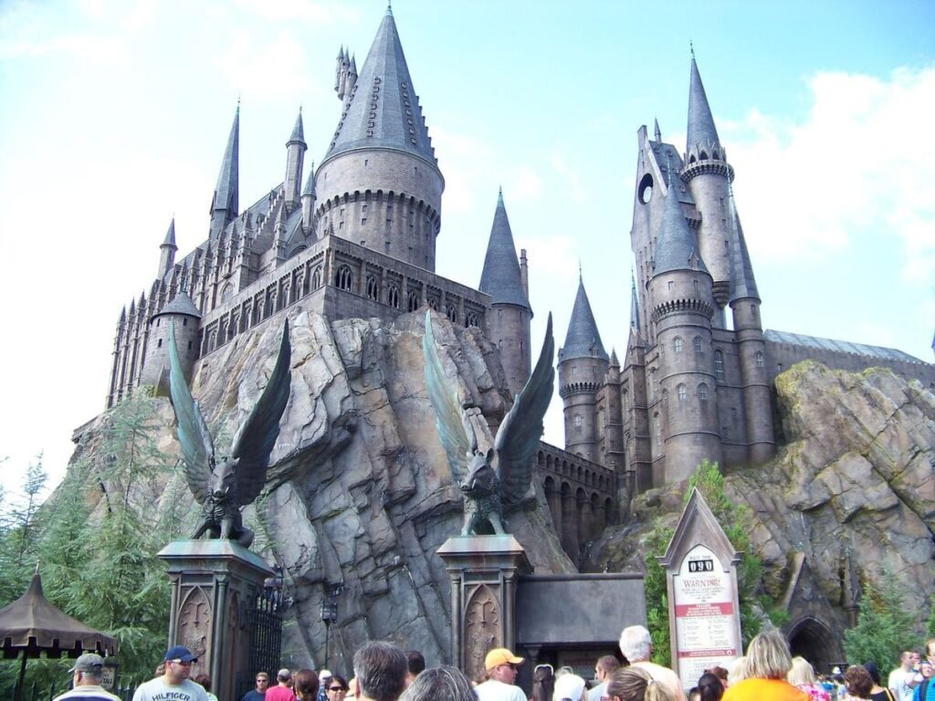 Visitantes explorando a vila de Hogsmeade com o castelo de Hogwarts ao fundo no parque Universal Studios Florida.